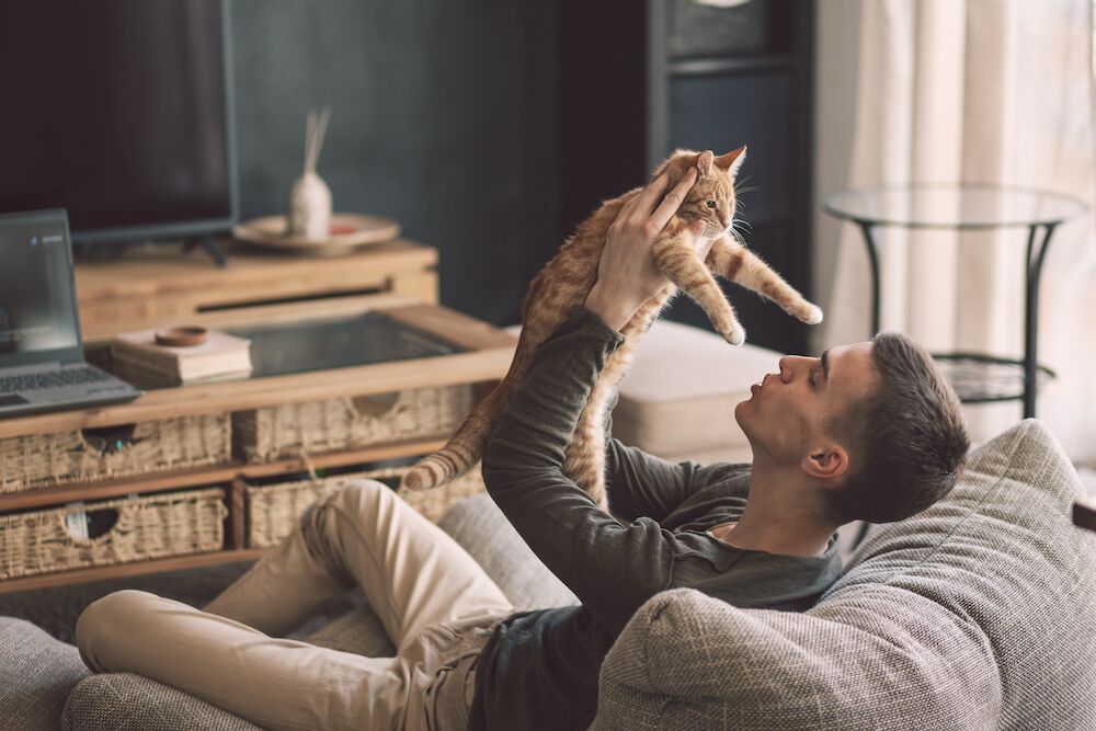 A man plays with his cat at the luxury apartments in KC