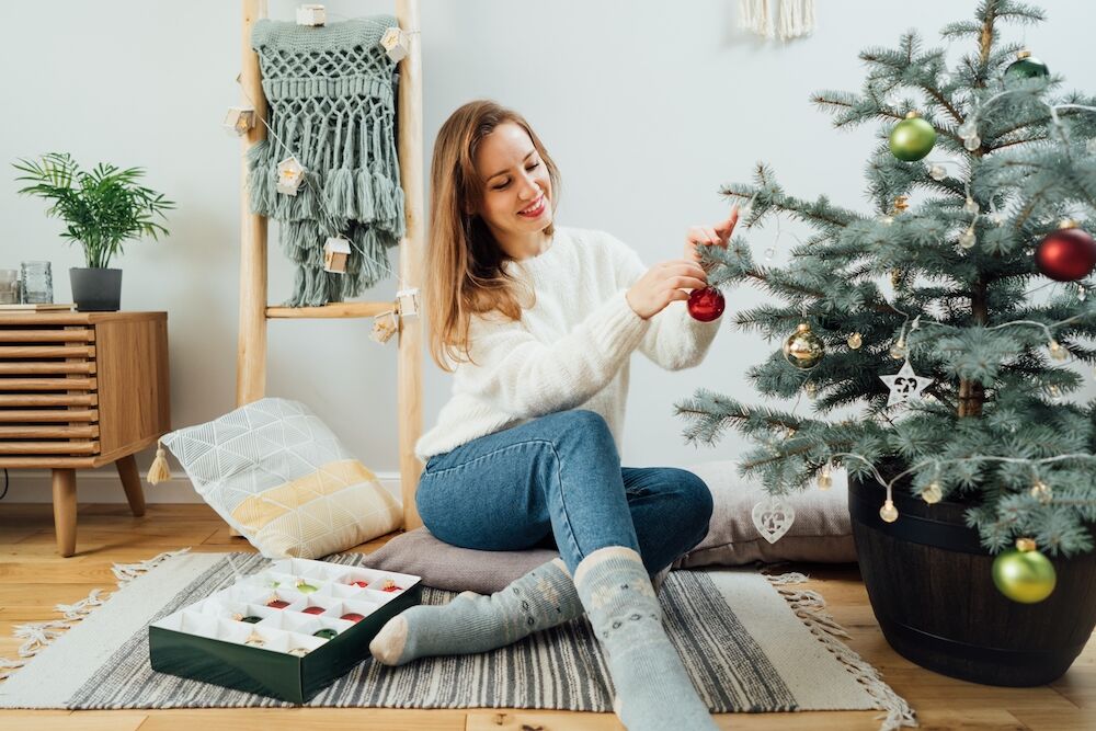 A young woman decorating a Christmas tree in her studio apartments in Kansas City