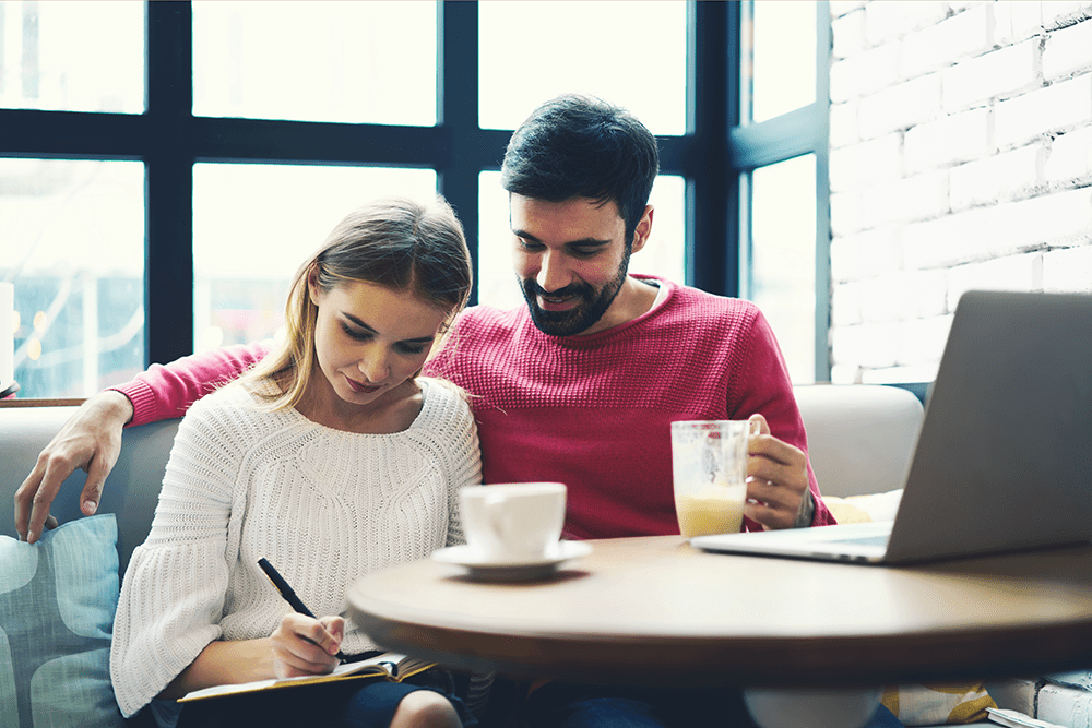 Couple sitting down, drinking coffee and making list