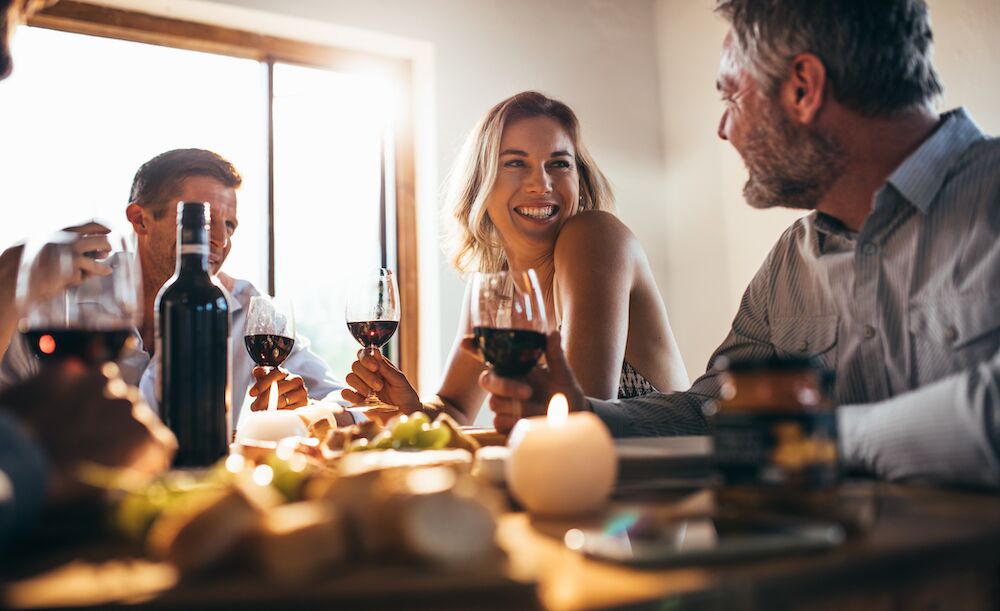 A group of friends talk and drink wine at a dinner party at the best apartments in Kansas City