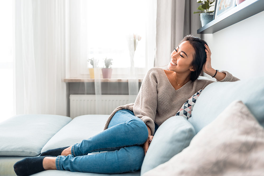 Woman smiling and sitting on couch in luxury apartment relaxing