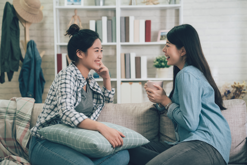Two friends talk together and drink coffee in Woodside apartments