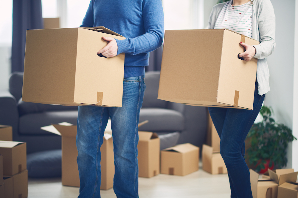 A couple carrying boxes into their apartment building