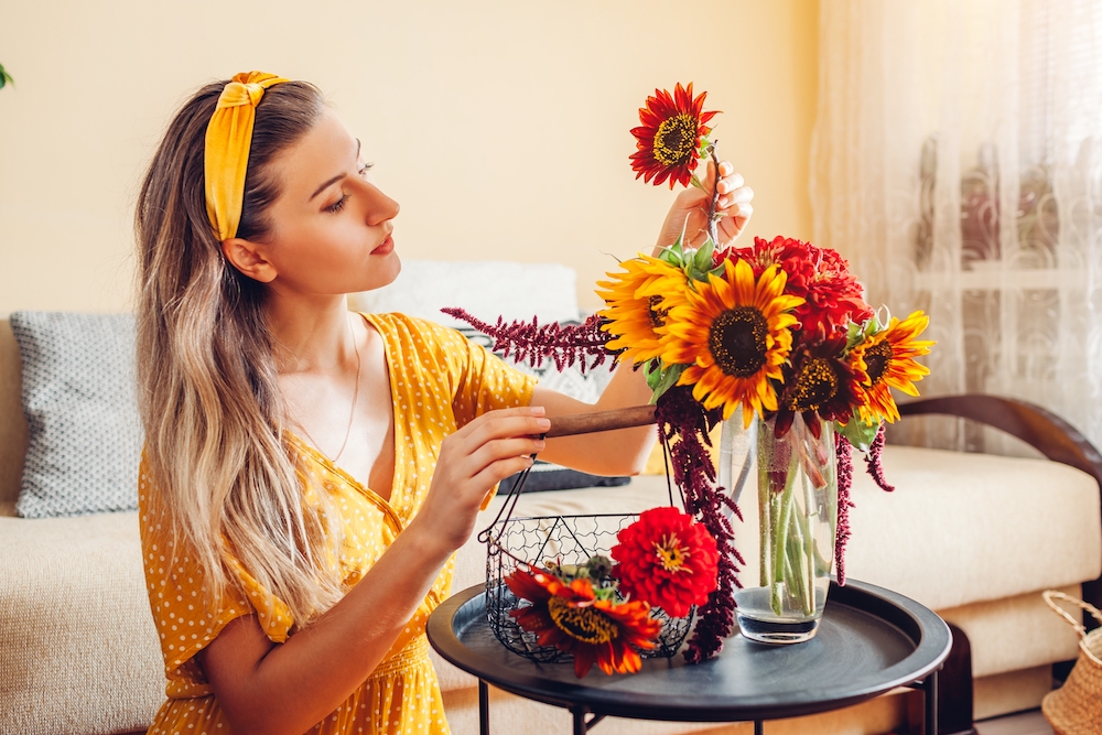 A woman organizing fall flowers in a vase