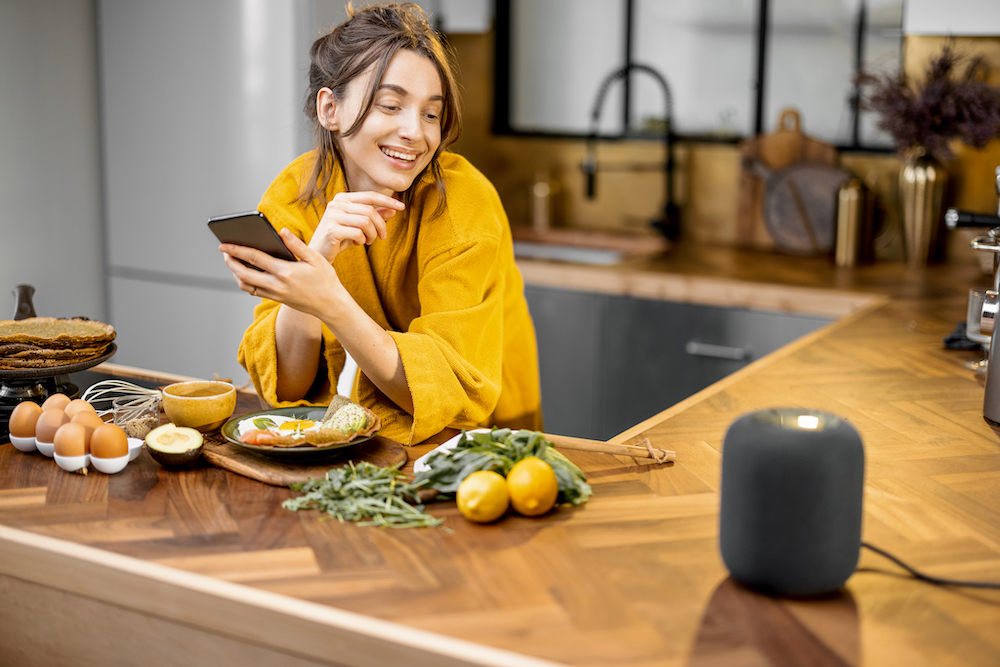 A woman cooking dinner while using a digital assistant home device