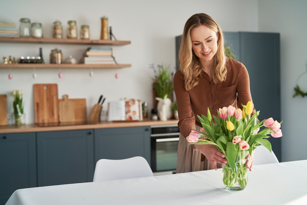 A woman putting a floral arrangement on her kitchen table at apartments for rent in Westwood