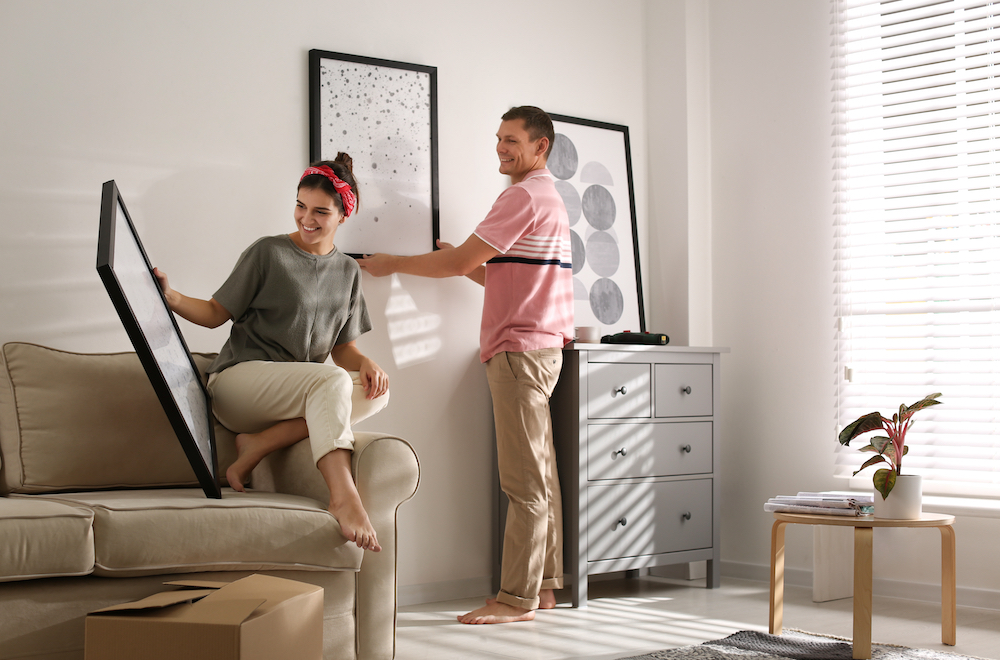 A happy young couple hangs up photos together in their new apartment