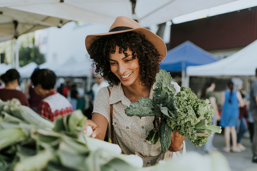 A young woman purchasing veggies at a farmers market near the Kansas City luxury apartments